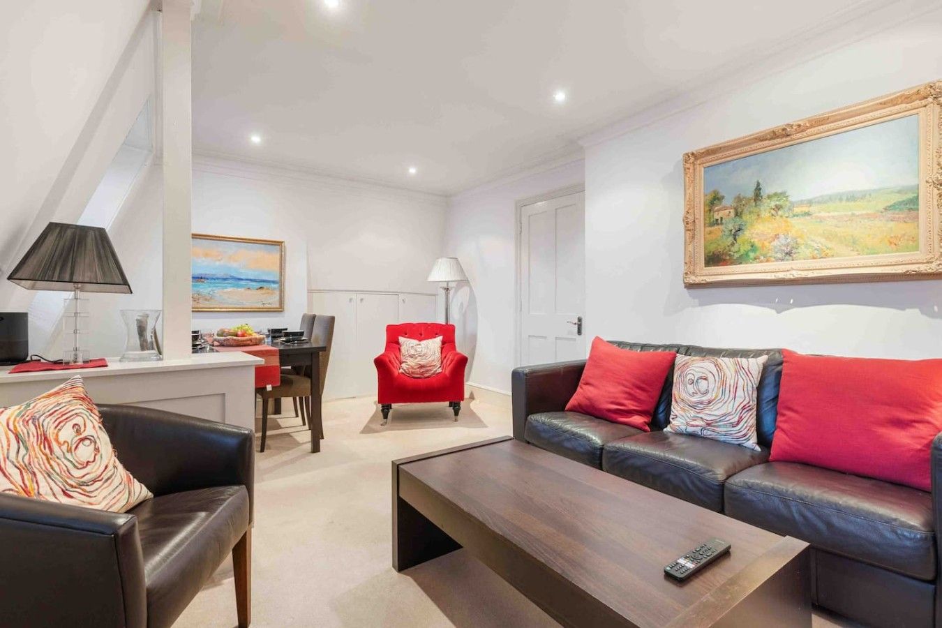 Un salon moderne avec un canapé, un fauteuil, une table basse et un tableau accroché au mur.