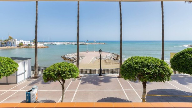 Un espacio al aire libre cubierto con vista al mar, una playa de arena y un promontorio rocoso.