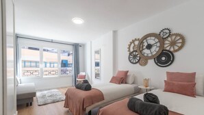 Una habitación de hotel moderna con dos camas, un ventanal grande y una pared decorada con engranajes.