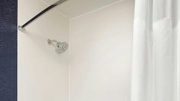 Un baño moderno con una bañera blanca, un cabezal de ducha de mano, un perchero de pared y un panel de control de ducha.