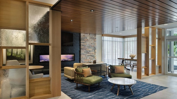 A modern living room with a stone wall, wooden ceiling, and a large window. - Fairfield by Marriott Inn & Suites Oxford (Oxford)