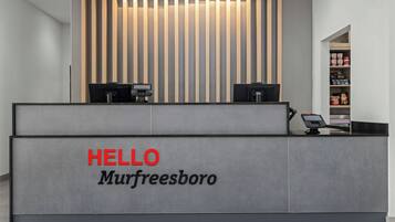 A reception desk with a 'HELLO Murfreesboro' sign, two computer monitors, and a shelf with various items.