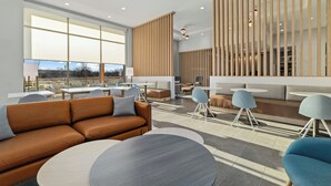 Een moderne zithoek met een bank, ronde tafels en een houten scheidingswand.