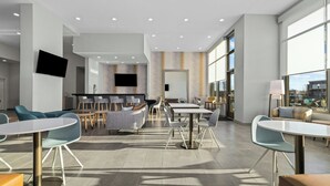 Een moderne hotellobby met zithoeken, een receptiebalie en grote ramen met uitzicht.