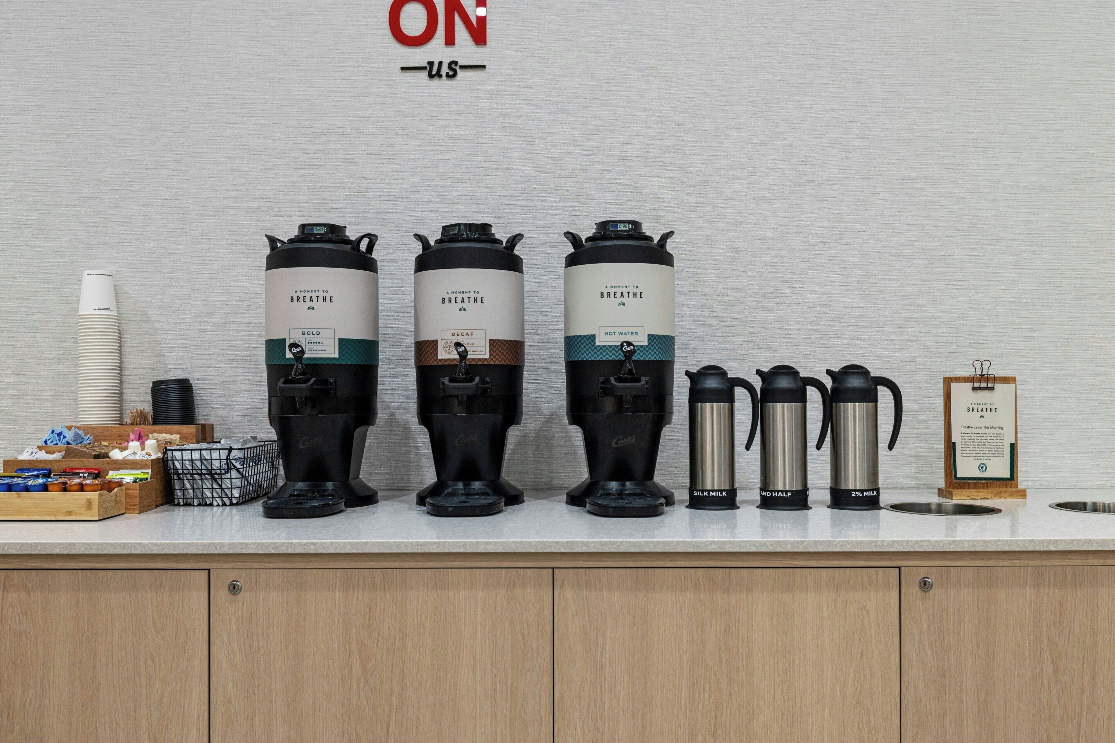 A kitchen counter with coffee makers, a coffee cup, and a menu.