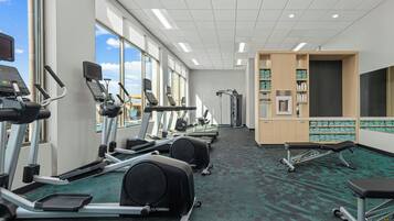 Une salle de sport équipée de tapis de course, de vélos elliptiques et d’un banc de musculation.