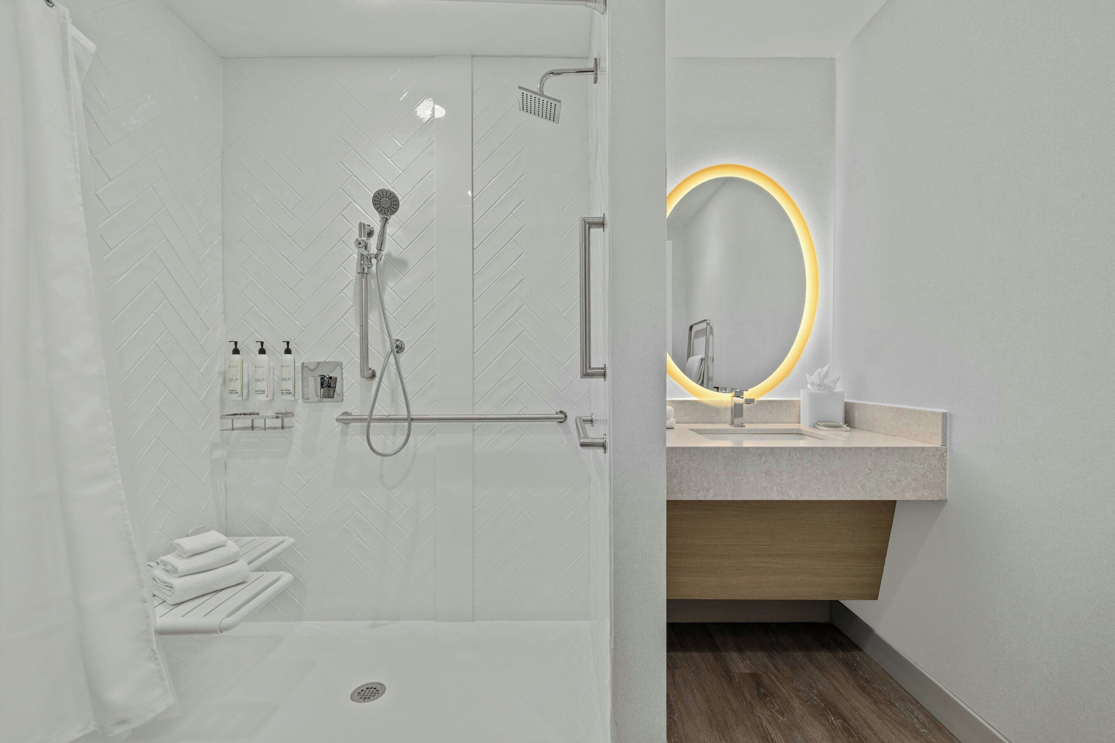 A modern bathroom with a shower, a vanity with a mirror, and a towel rack.