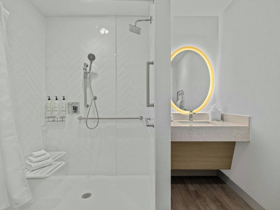 A modern bathroom with a shower, a vanity with a mirror, and a towel rack.