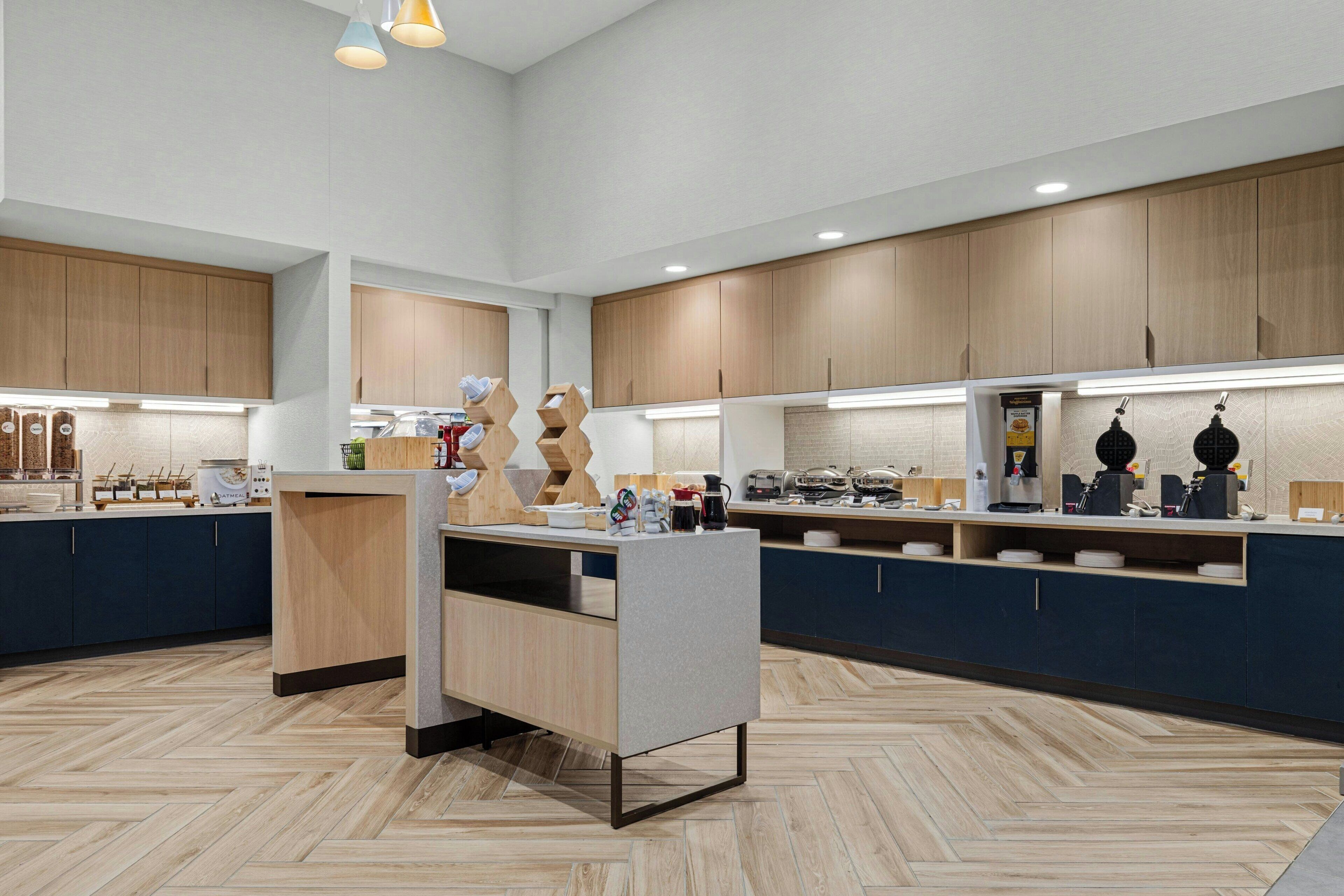 A modern kitchen with wooden cabinets, a central island, and built-in appliances.