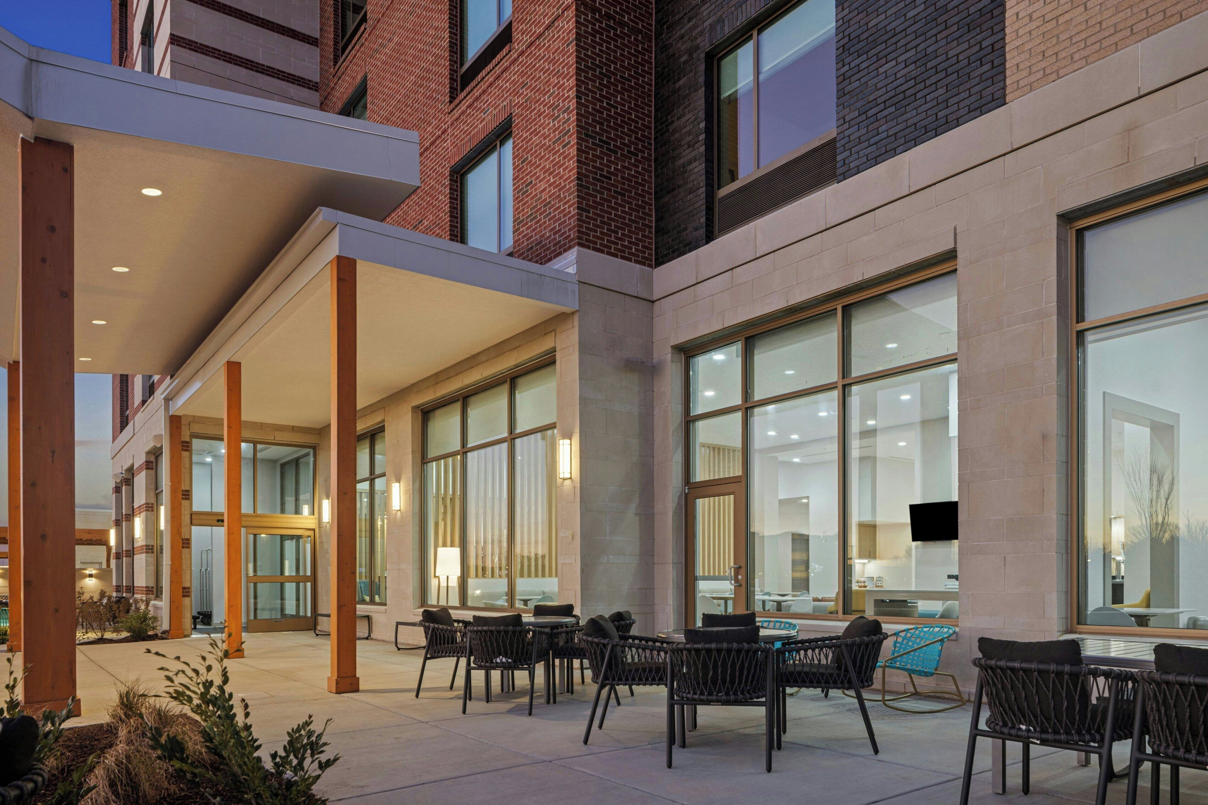 Un patio al aire libre con mobiliario y acceso a un edificio.