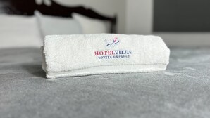 Una toalla blanca doblada con cuidado y texto bordado sobre una cama.