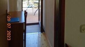 A narrow hallway with a door leading to an outdoor patio area. A small table and chairs are visible outside. - ROOMS MATEA PULA (Vodnjan)