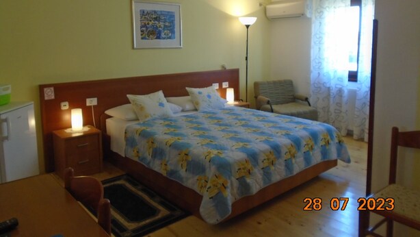 A hotel room with a bed, bedside lamps, a chair, a desk, and a window with curtains. - ROOMS MATEA PULA (Vodnjan)