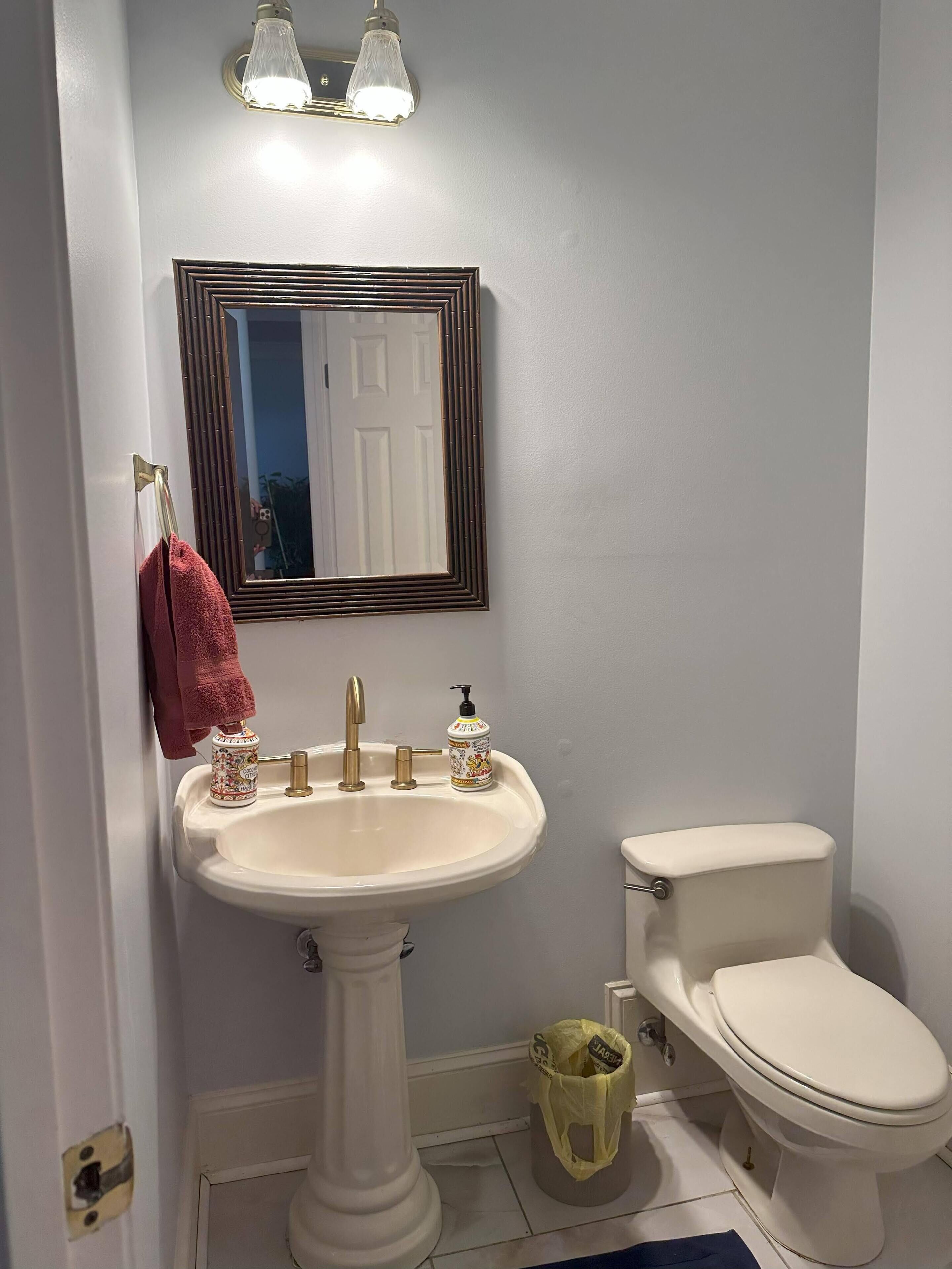 Une salle de bain équipée d’un lavabo sur colonne, de toilettes, d’un miroir et d’un porte-serviettes.