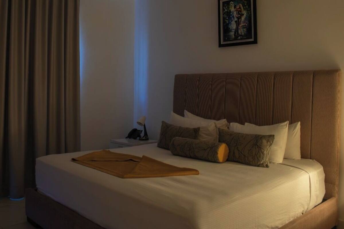 A hotel room with a large bed, a headboard, and a painting on the wall.