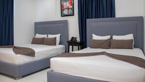 Habitación de hotel con dos camas, cada una con cabecera, mesita de noche y un cuadro enmarcado en la pared.