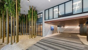 A modern indoor space with a central staircase, glass walls, and vertical greenery.