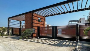 Una entrada protegida con una verja metálica y una estructura de pérgola.