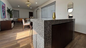 Una cocina moderna con encimera de granito, un mueble de madera oscura y una zona de comedor con mesa y sillas.