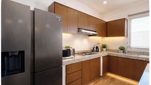 Una cocina moderna con electrodomésticos de acero inoxidable, armarios de madera y encimeras de granito, e incluye una estufa integrada.