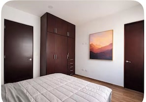 Ein Schlafzimmer mit einem Bett, einem Kleiderschrank und einem Bild an der Wand.