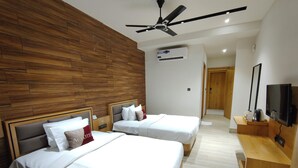A hotel room with two beds, a ceiling fan, an air conditioning unit, a TV, and a wooden bench. - Aceotel Premier TK Morbi (Morbi)