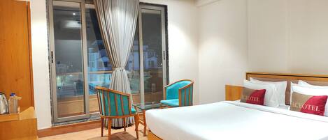 A modern hotel room with a large bed, a desk, and a chair.