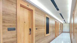 A modern hotel hallway with wooden doors, a tiled floor, and recessed lighting. - Aceotel Premier TK Morbi (Morbi)