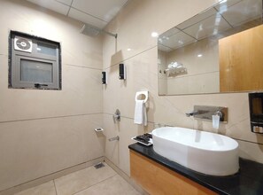 A modern bathroom with a large mirror, a white sink, and a shower area. - Aceotel Premier TK Morbi (Morbi)