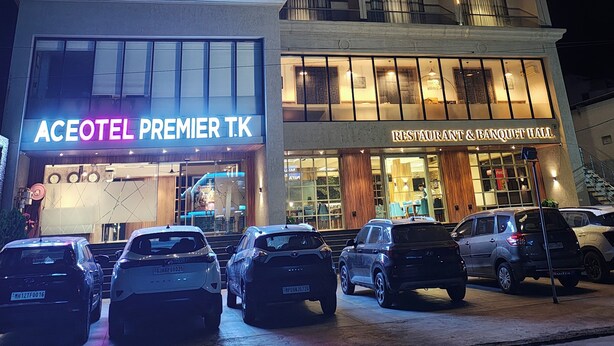 A multi-story hotel with a prominent sign for "Aceotel Premier T.K" and a "Restaurant & Banquet Hall" below. Several cars are parked in front. - Aceotel Premier TK Morbi (Morbi)