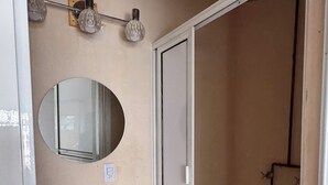 Un baño con un lavamanos blanco, un espejo y una cabina de ducha.