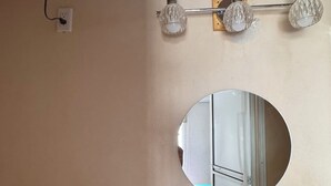 Un baño con un lavamanos blanco, un espejo, un dispensador de papel higiénico e iluminación empotrada en la pared.