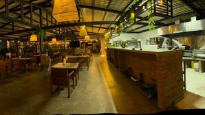 Un restaurante con techo alto, luces colgantes y vistas al atardecer.