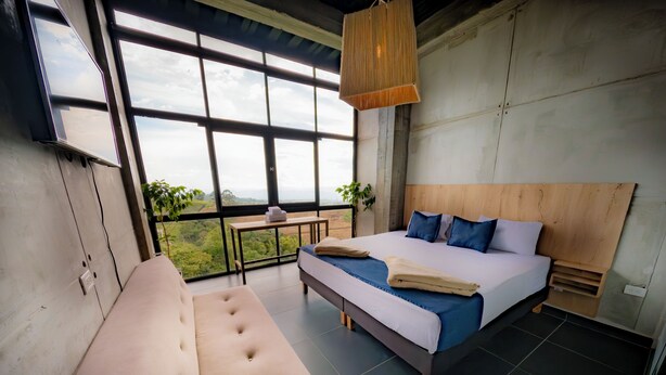 Un dormitorio moderno con una cama grande, un sofá y vistas al exterior.