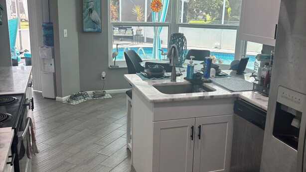 A modern kitchen with a built-in dishwasher, a sink, and a window overlooking a backyard. - Charming 2-bedroom pool home with AC, WiFi in Lehigh Acres (Lehigh Acres)