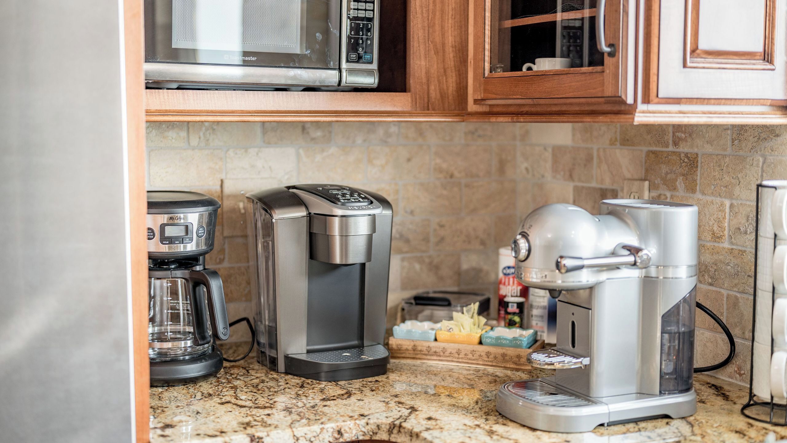 A kitchen with a coffee maker, a toaster, and a microwave.
