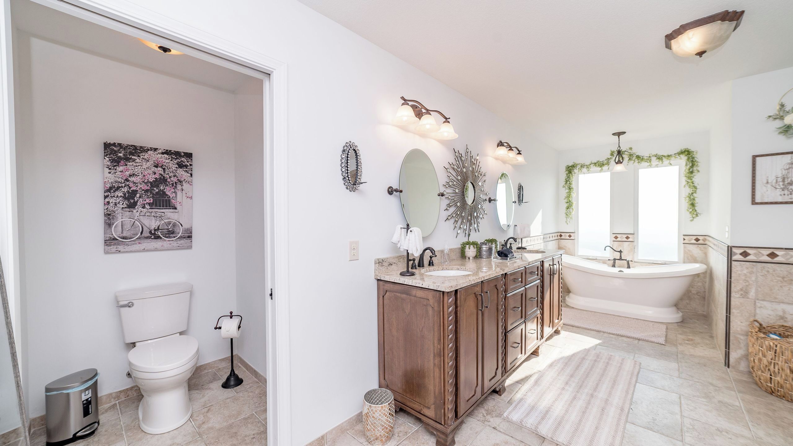 Une salle de bain comprenant des toilettes, un lavabo et une baignoire, des meubles en bois et des miroirs décoratifs.