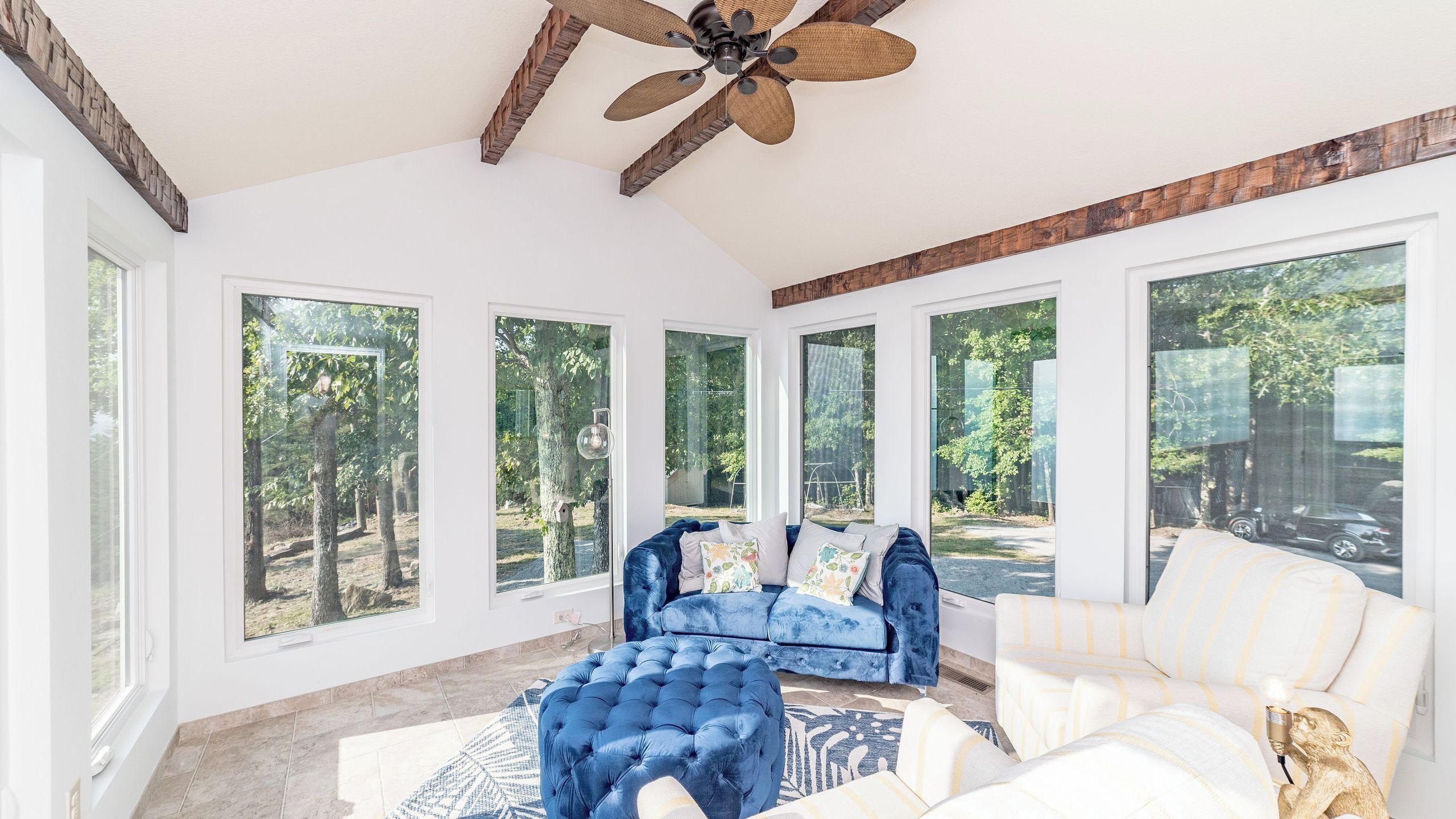 A spacious room with large windows, a ceiling fan, and a blue sofa.