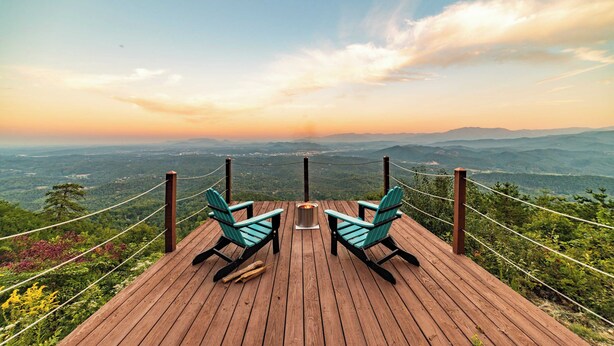 A wooden deck with two chairs and a fire pit, overlooking a mountainous landscape. - Panorama by Avantstay Unparalleled Views, Deck w/ Hottub, Game Room Pool Table (Sevierville)