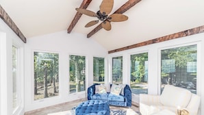 A sunlit room with a large window, a blue sofa, a white sofa, and a tufted ottoman. - Panorama by Avantstay Unparalleled Views, Deck w/ Hottub, Game Room Pool Table (Sevierville)