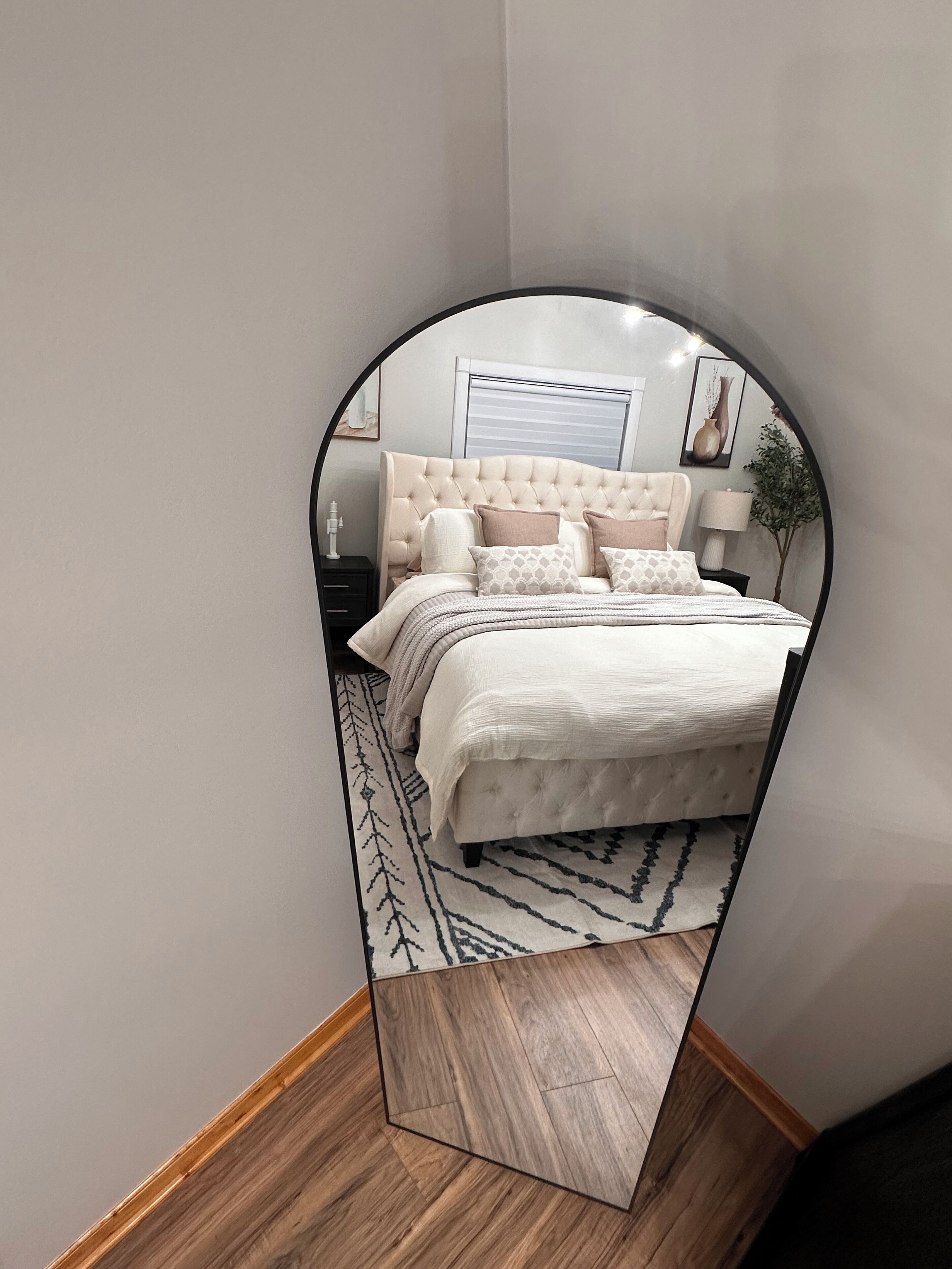 Une chambre à coucher avec un lit, une table de chevet, une lampe et un miroir.