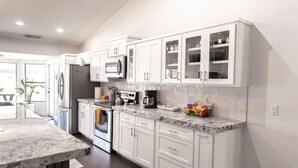 A modern kitchen with white cabinetry, a granite countertop, and stainless steel appliances. - Spring training fields less than 10 miles, heated pool, e-bikes, sleeps 10 (Peoria)