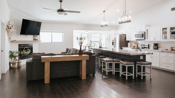 A modern kitchen with white cabinets, a large island with bar stools, and a ceiling fan. - Spring training fields less than 10 miles, heated pool, e-bikes, sleeps 10 (Peoria)