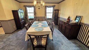 A dining room with a long table set for six, flanked by dark wood cabinets and a vintage clock. - Charming House With 3 Bed/3 Bath in Ft. Pierce, FL (Fort Pierce)