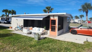 A modern beach house with a covered patio, outdoor seating, and a bicycle.