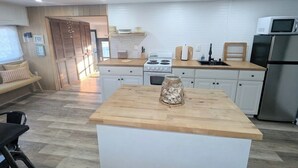 A modern kitchen with white cabinets, a wooden countertop, and stainless steel appliances.