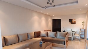 Ein modernes Wohnzimmer mit einer Eckcouch, einem Couchtisch und einem Essbereich mit Stühlen und einem kleinen Tisch.