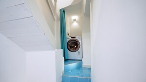 Un lavadero con lavadora y escaleras con azulejos azules.