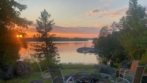 A lakeside view with chairs and a fire pit.