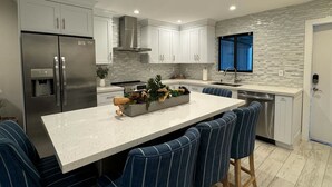 A modern kitchen with a central island, stainless steel appliances, and a backsplash.